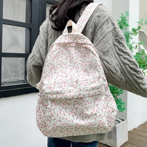 Floral canvas backpack with pink flower prints on cream white shown on a model's back