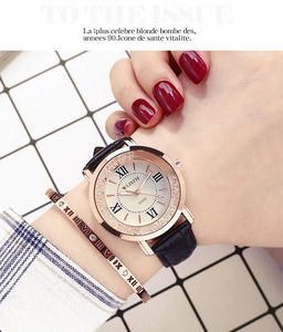 Detail of rose gold quartz watch with rhinestones and black leather strap on wrist