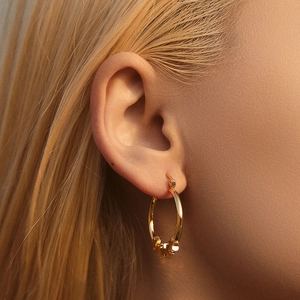 Macro side view of elegant 18K gold-plated hoop earrings with small star pendants