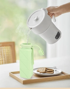 Pouring hot water from white kettle into a light green collapsible silicone water bottle