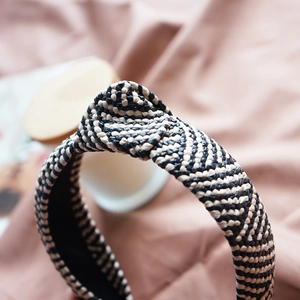 Macro view of woven raffia headband showing detailed black and beige knotted design