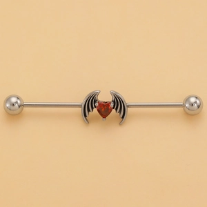 Detail of stainless steel industrial barbell with a red heart gem and metal wings charm