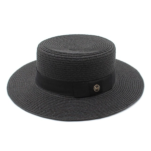 Détail du chapeau de paille noir avec ruban gros-grain et badge métallique doré M