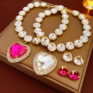 Close-up of luxury gold-plated necklace set featuring pink heart crystals and clear stones