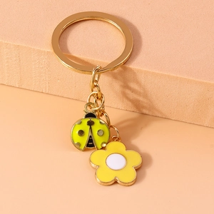 Close-up of golden ladybug and yellow flower keychain with enamel texture