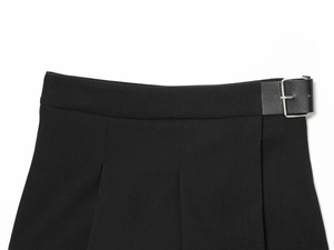 Détail de la taille d'une jupe noire avec bride latérale en cuir et boucle argentée