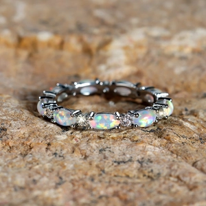 Macro detail of oval opal ring with pavé diamonds on a natural stone background