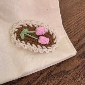 Detailed crochet texture of handmade pink tulips and green leaves embroidery hair clip