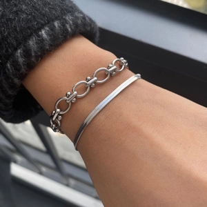 Nahaufnahme des gestapelten silbernen Gliederarmbands und der flachen Schlangenkette