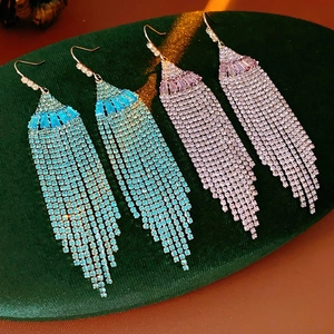 Macro shot of long rhinestone tassel earrings in blue-green and pink-purple gradients