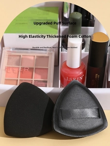Macro detail of black triangular makeup puffs with silky ribbon handles and soft flocking
