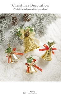 Close-up of gold Christmas bells with red bows and pine needles on faux snow background