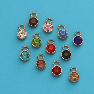 Flat lay of 12 colorful birthstone charms with gold metal bases on a blue background