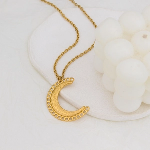Élégant collier pendentif croissant de lune doré sur plateau décoratif blanc