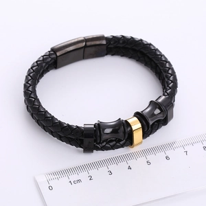 Detail of black braided leather bracelet with gold metal beads and magnetic clasp