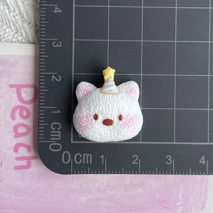Top view of a small resin white cat figurine with a birthday hat on a metric cutting mat