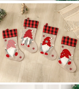 Detail of four burlap Christmas stockings with gnome motifs on rustic wood floor background