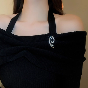 Vue détaillée d'une broche spirale avec zircons et perle blanche sur tissu noir