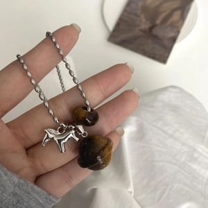Close-up of silver horse pendant with tiger eye stone bead on a round bead chain