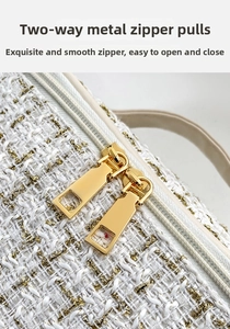 Detail of tweed makeup bag with dual golden metal zippers and premium woven texture