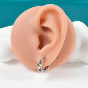 Macro view of silver punk spiked hoop earring with rock texture on a silicone ear model