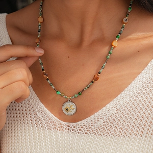 Detail of bohemian beaded necklace with moon and sun engraved pendant on model