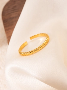 Close-up of a 18k gold plated twisted rope ring on a soft white silk background