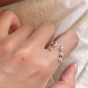 Irregular silver lava-style open ring shown on a finger with a minimalist fabric background