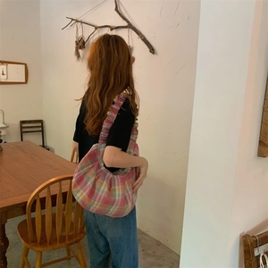 Detail of a pink and yellow plaid canvas tote bag worn as a shoulder hobo bag