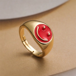 Close-up of golden wide-band ring with red enamel smiley face and open adjustable design