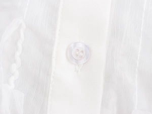 Detailed macro view of white shirt fabric texture and translucent round button detail