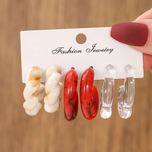 Close-up of three pairs of marble-textured resin C-hoop earrings on a display card