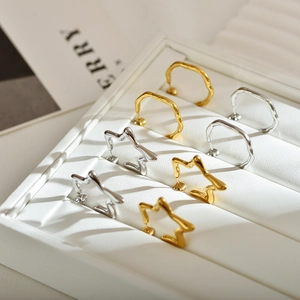 Minimalist gold and silver star hoop earrings displayed in a white leather jewelry box