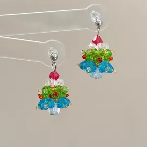 Detailed close-up of handmade beaded Christmas tree earrings with colorful crystal beads