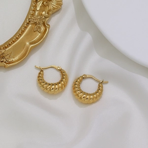 Macro shot of 18K gold plated croissant hoop earrings on white silk background