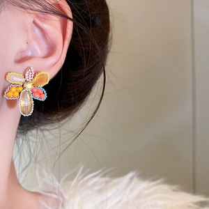 Detailed close-up of a colorful crystal flower stud earring worn on a model's ear.