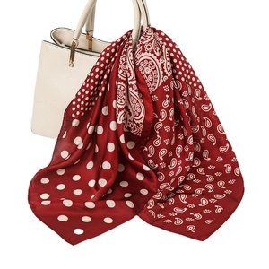 Red paisley and white polka dot silk scarf tied on a white handbag handle