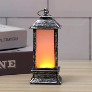 Close-up of antique silver LED lantern with warm orange glow on a wooden desk scenery