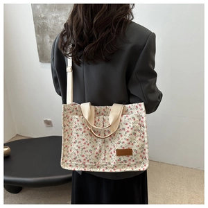 Floral canvas tote bag shown on model featuring a beige floral pattern and brown label