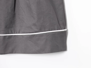 Detailed close-up of dark grey poplin fabric featuring white contrast piping and fine texture
