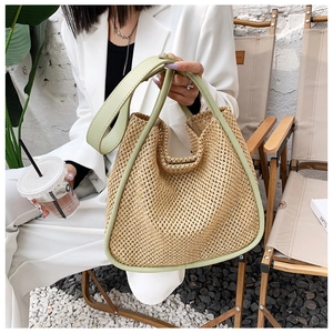 Detailed close-up of woven straw tote bag with green leather trim and hollow pattern