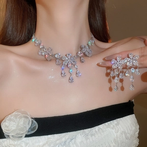 Close-up of elegant flower and teardrop zircon pendant necklace and earrings set on model