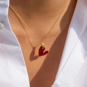 Collana retrò dorata con ciondolo a cuore rosso glitterato indossata su una modella