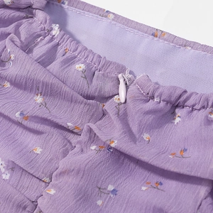 Dettaglio della cerniera invisibile su abito in chiffon floreale con motivi eleganti