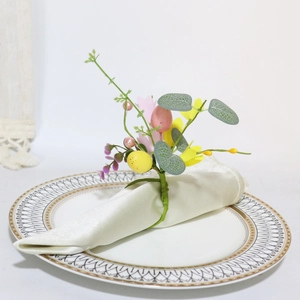 Easter napkin ring with colorful eggs and spring flowers on a white napkin with a gold-rimmed plate