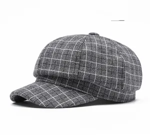 Close-up of light gray plaid texture and button detail on vintage newsboy cap