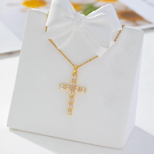 Detail of gold cross pendant with white rhinestones on white bow display stand