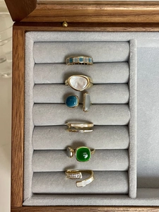 Detail of assorted vintage emerald and shell rings in a jewelry box organizer