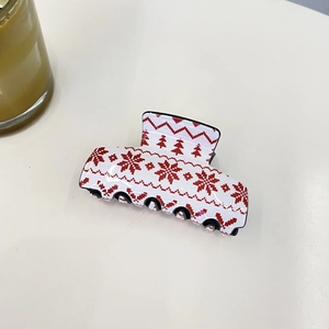 Detailed view of white Christmas claw clip with red snowflake and reindeer patterns