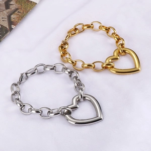Detailed view of chunky gold and silver heart pendants on O-shaped link bracelets